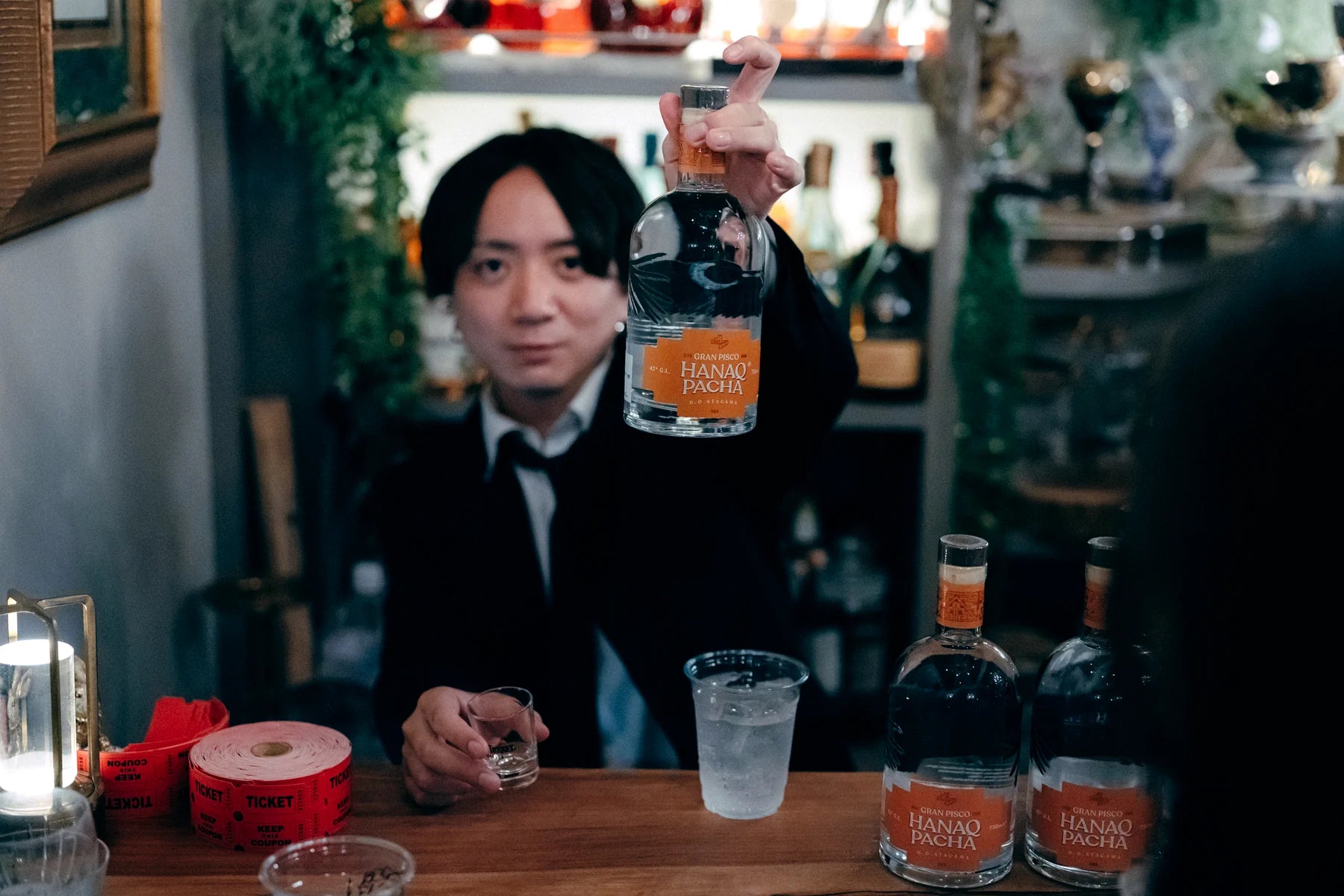 Bartender presentando botella Hanaq Pacha en barra profesional