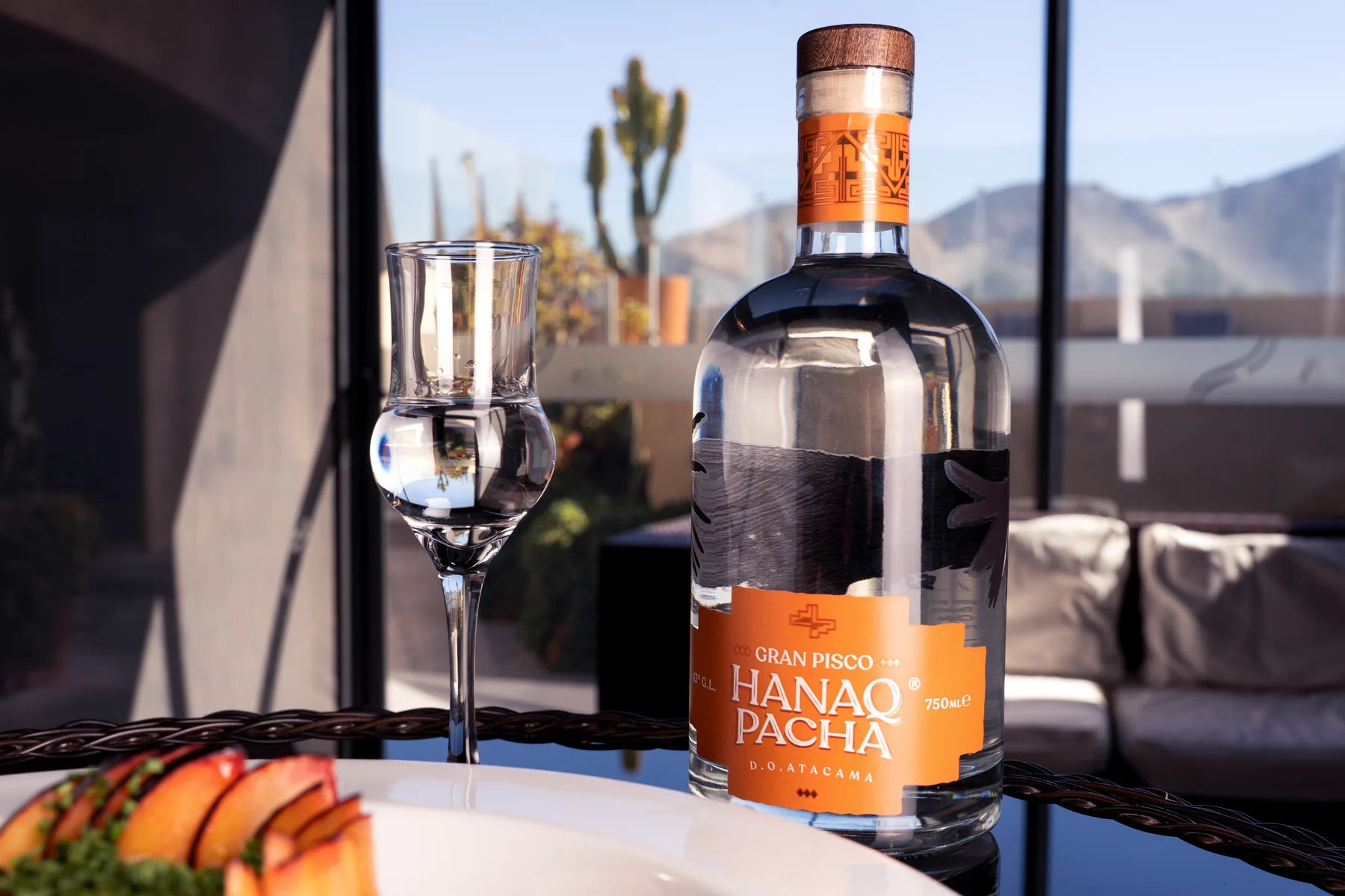 Botella Hanaq Pacha y copa en terraza con vista al valle