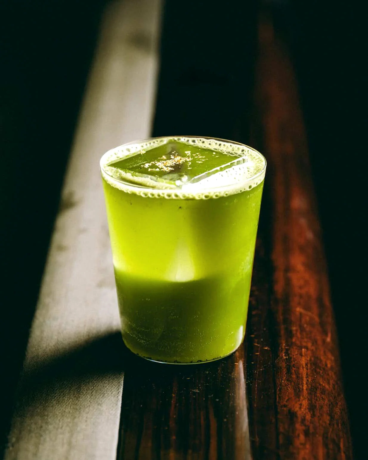 Coctel verde en vaso bajo con luz de barra